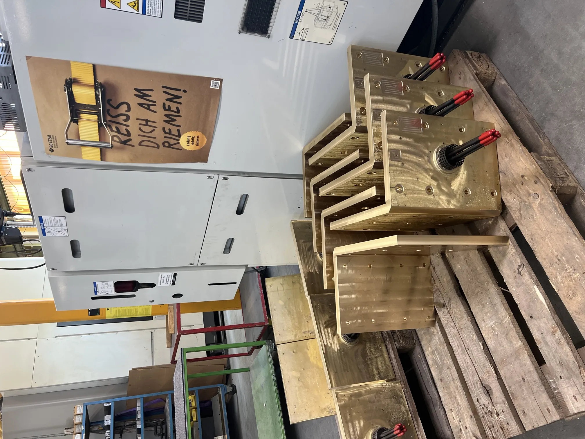 Fertig bearbeitete Werkzeugbeheizungen aus Messingguss auf Palette vor dem Bearbeitungszentrum